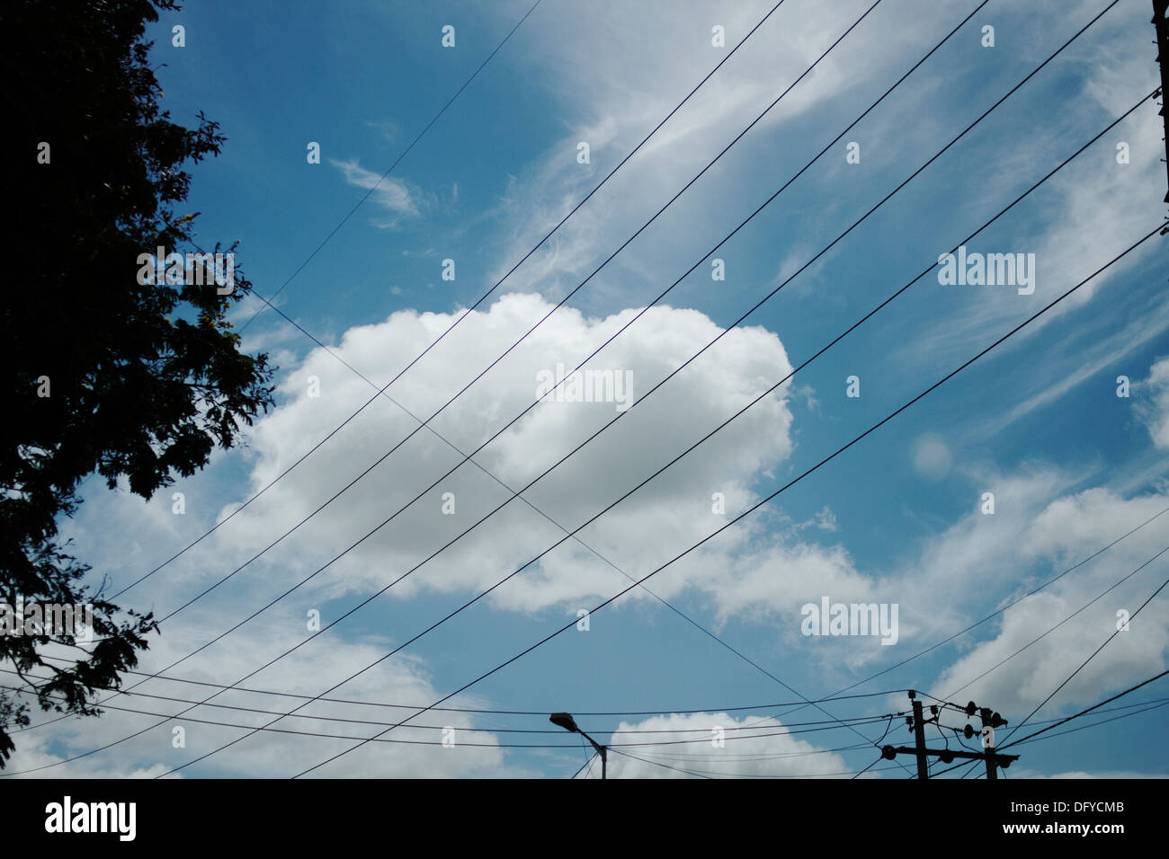 Cloud e il blu del cielo visto attraverso una fila di cavi elettrici. Foto Stock