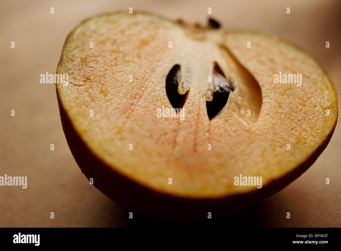 Sapodilla. Una fresca tagliata a fette la metà del frutto è impostata su uno sfondo di colore marrone Foto Stock