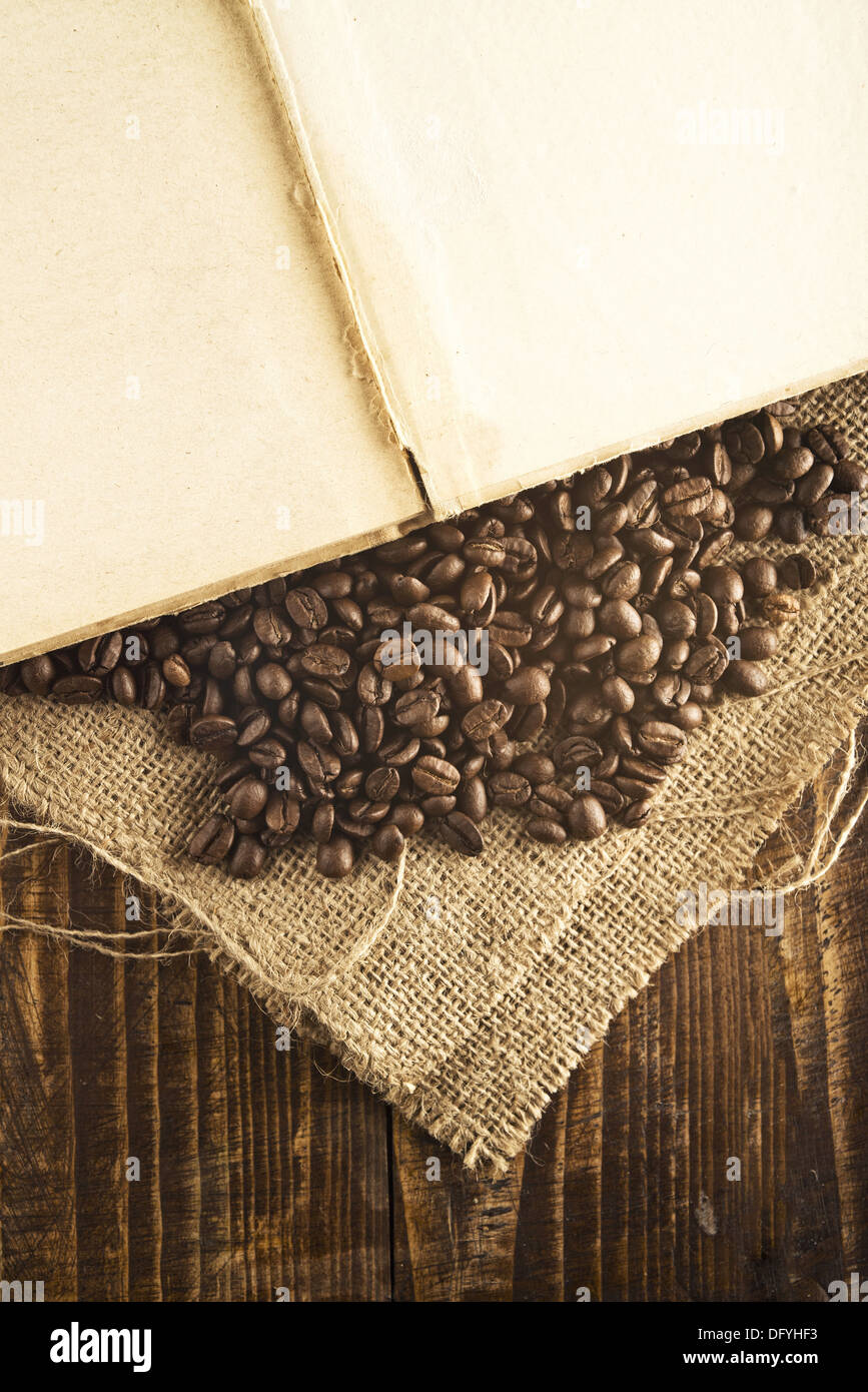 I chicchi di caffè e libro aperto sulla tela di iuta di texture. Foto Stock