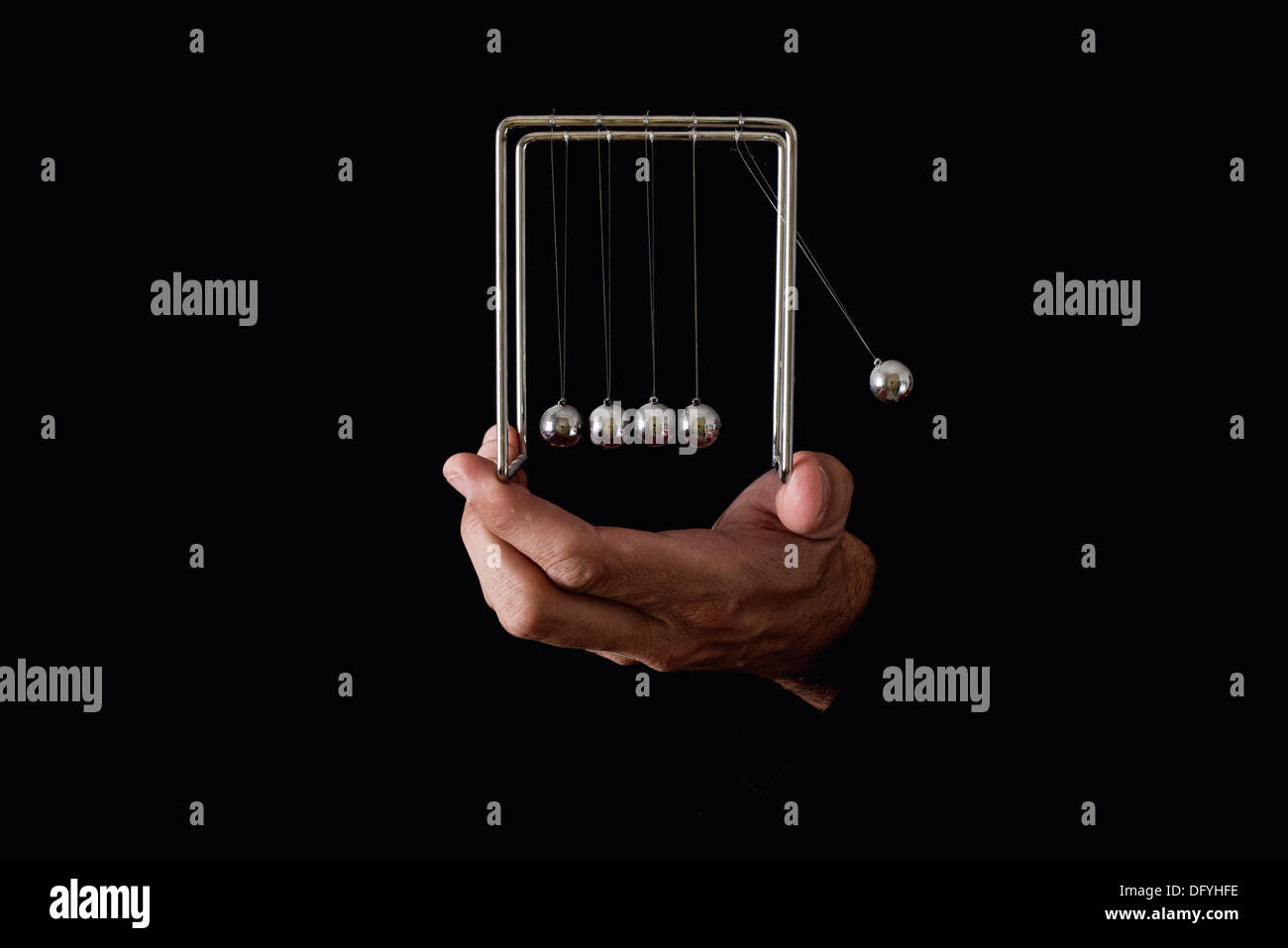 Newton del pendolo o culla in mani umane su sfondo scuro Foto Stock