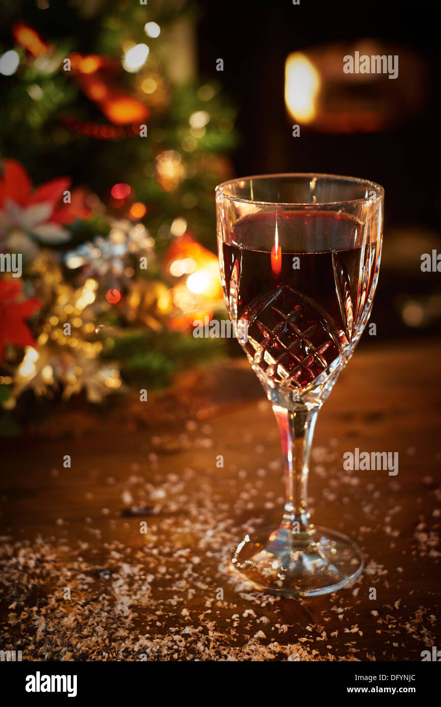 Un albero di Natale di scena a notte con un bicchiere di vino rosso e decorazione di Natale. Foto Stock