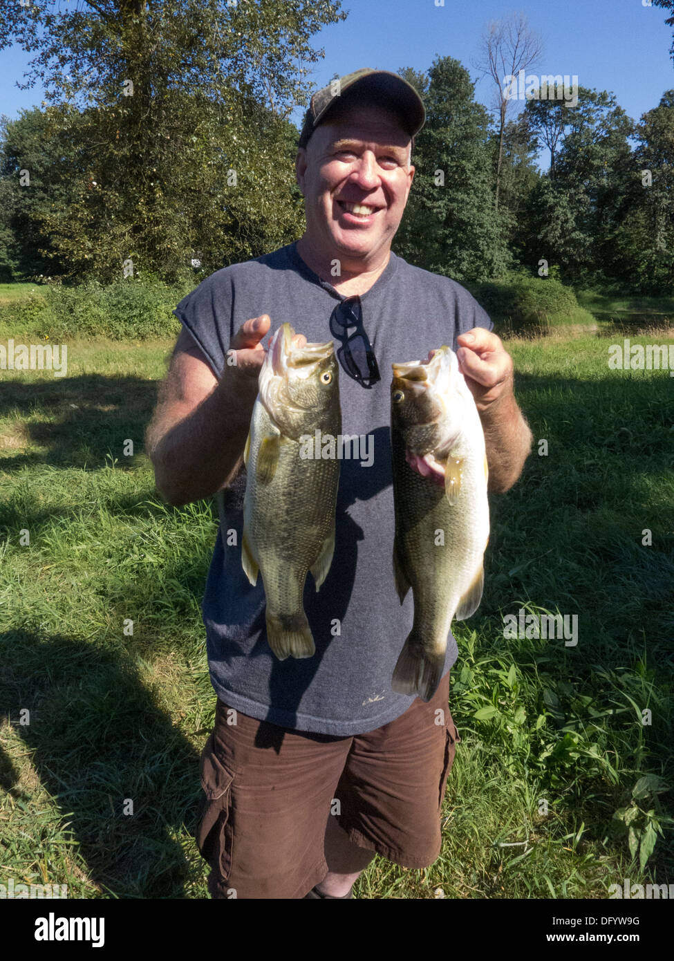Bass fisherman visualizza grande bocca bass ha catturato in un slough vicino Monroe,Washington. Foto Stock