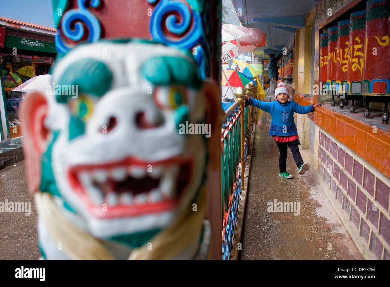 Ragazza e ruote della preghiera, in Main Bazar street,McLeod Ganj Dharamsala, Himachal Pradesh, India, Asia Foto Stock