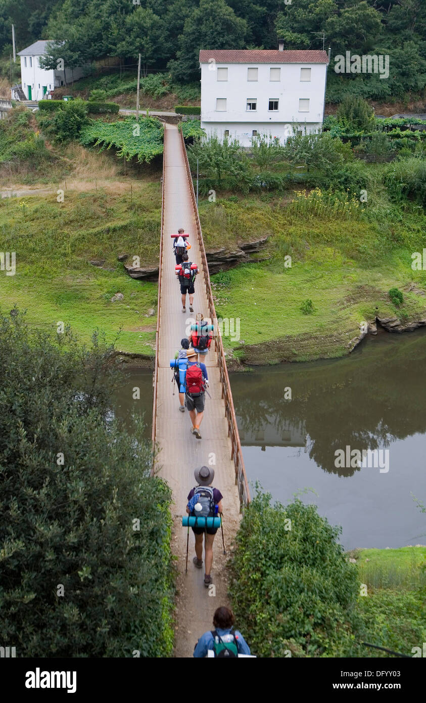 Pellegrini in cammino attraverso il ponte per andare fuori Portomarín. Arroyo Torres. Foto Stock