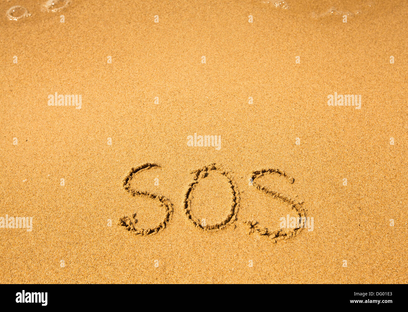 SOS - scritto nella sabbia sulla spiaggia, soft onda di mare. Foto Stock