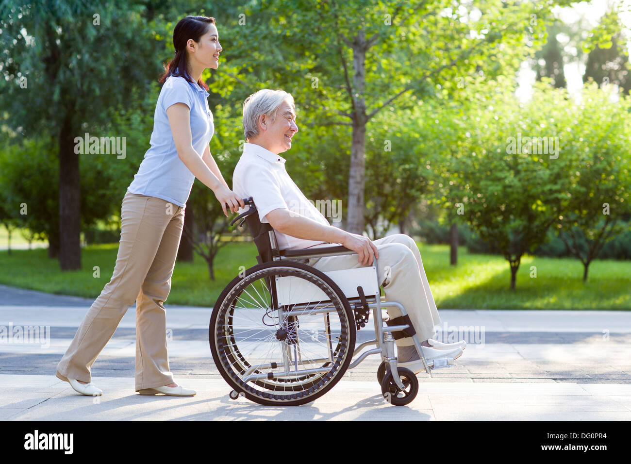 Sedia a rotelle uomo legato con assistente infermieristica Foto Stock