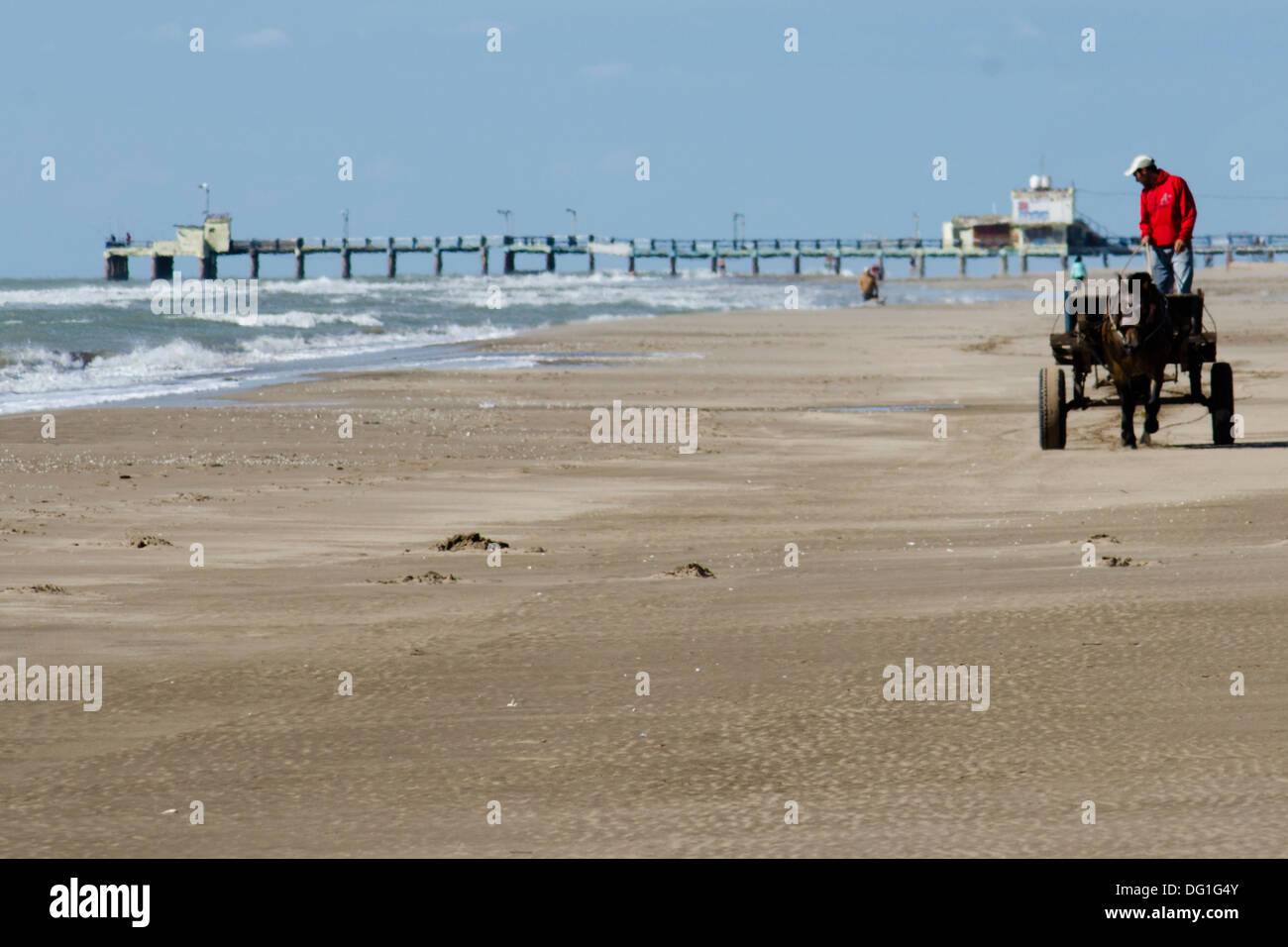 Persone che utilizzano il carro cavalli per trasportare la sabbia in spiaggia da utilizzare come materiali di costruzione. San Clemante del Tuyu, Argantina Foto Stock