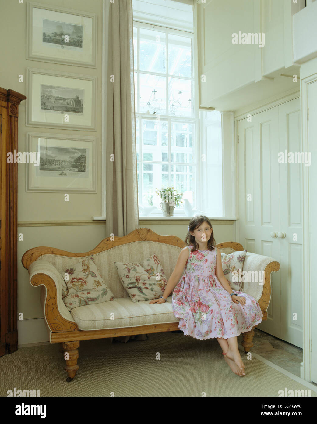 Ritratto di bambina indossa un abito piuttosto seduto sul divano nel paese hall Foto Stock