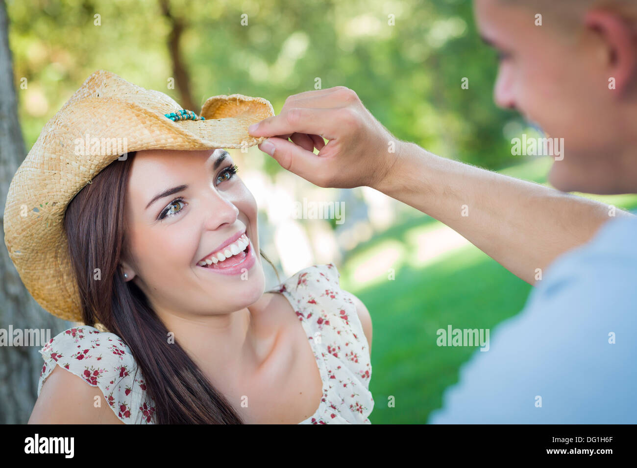 Felice razza mista coppia romantica con il cappello da cowboy flirtare nel parco. Foto Stock