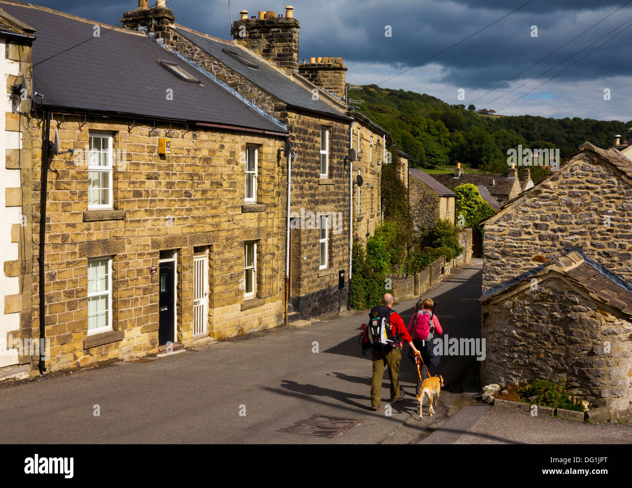 I camminatori con cane passando Casolari tradizionali in Eyam noto come la peste village Derbyshire Peak District Inghilterra REGNO UNITO Foto Stock