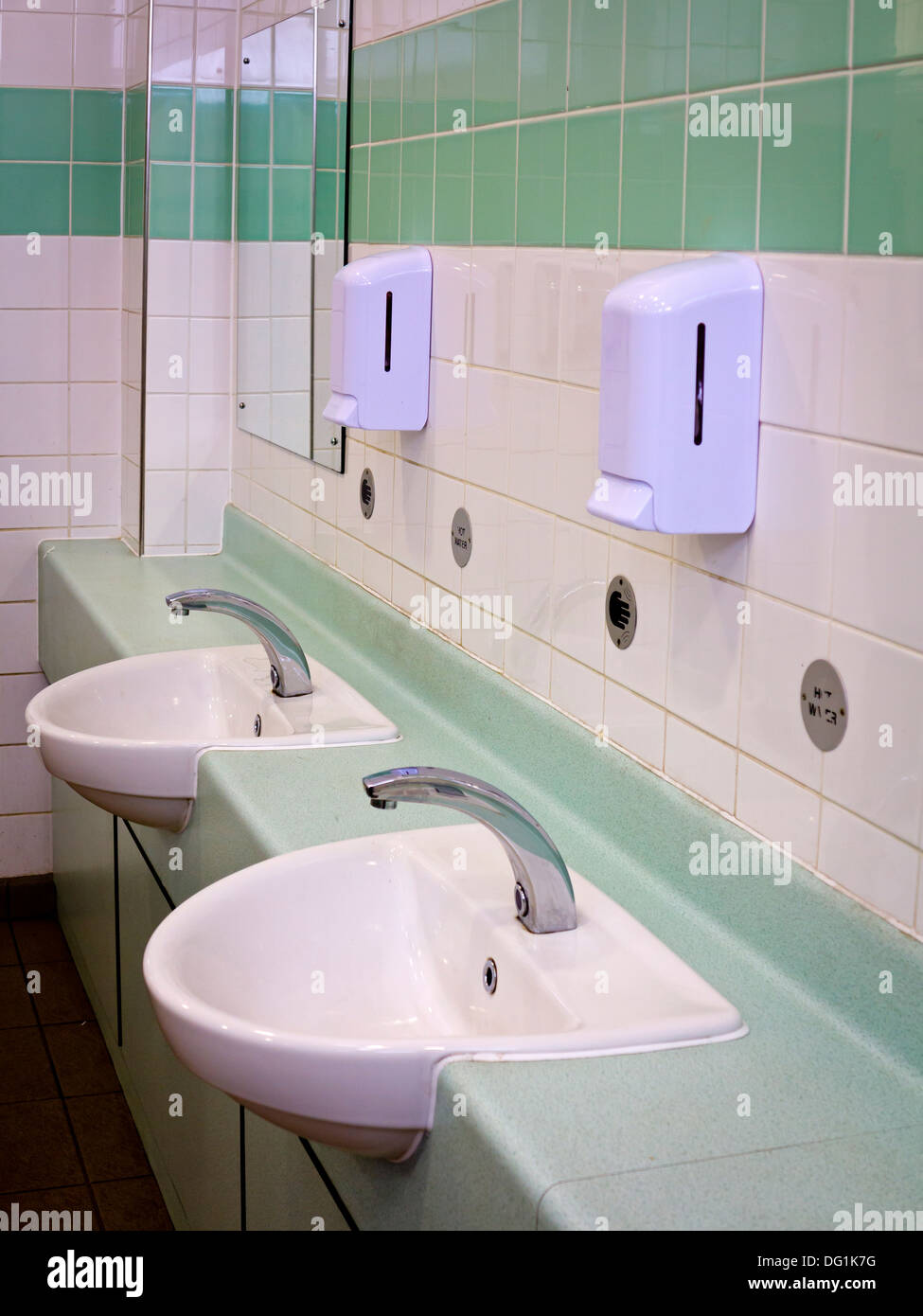 Lavabi e Dosatori del sapone in un wc pubblico con pareti piastrellate Foto Stock
