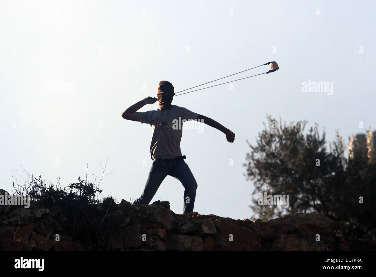 Ramallah, West Bank, Territorio palestinese . Undicesimo oct, 2013. Un manifestante palestinese utilizza un slingshot per scagliare pietre durante gli scontri con i soldati israeliani in Betunia vicino al West Bank città di Ramallah il 11 ottobre 2013. Credito: ZUMA Press, Inc./Alamy Live News Foto Stock