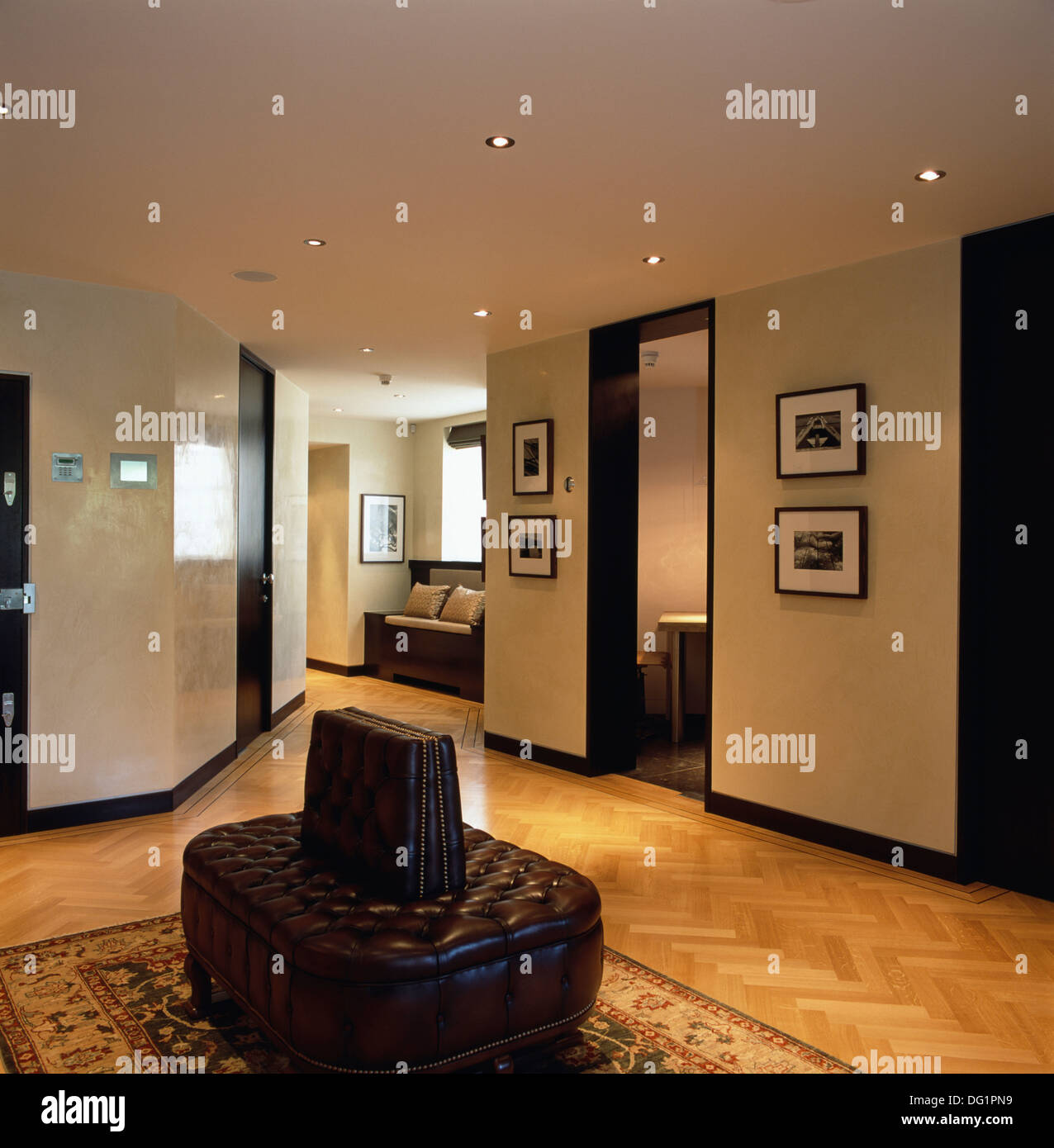 Pelle marrone pulsante sedile supportato in moderno appartamento sala con pavimento in parquet e illuminazione a incasso Foto Stock