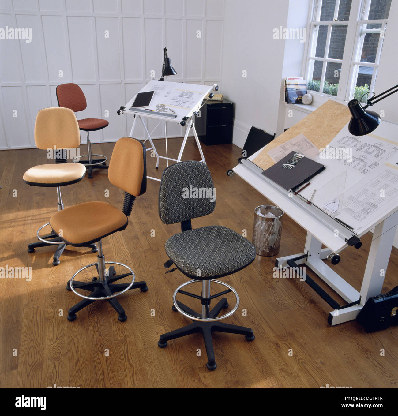 Il marrone ed il grigio ufficio girevole sedie in studio ufficio commerciale con tavole da disegno e il pavimento in legno Foto Stock