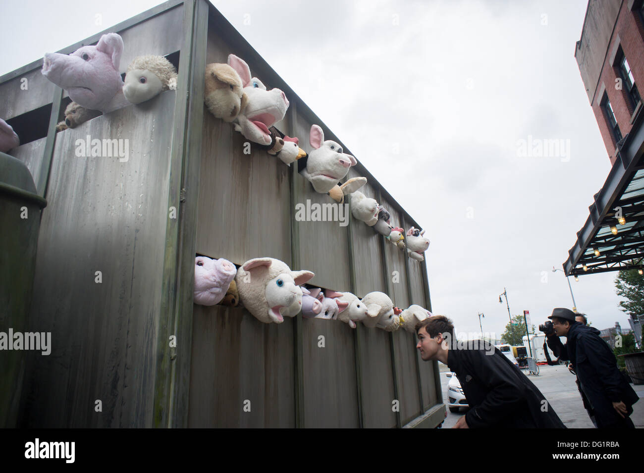 New York City, NY, STATI UNITI D'AMERICA. Undicesimo oct, 2013. Gli appassionati di Banksy gregge del quartiere alla moda di Meatpacking District di New York su Venerdì, Ottobre 11, 2013 per vedere l'undicesima puntata di Banksy arte, "Le Sirene degli agnelli". Questo particolare pezzo scultoreo consiste in un macello carrello riempito con belati animali di peluche, controllata da burattinai, che furono condotti in giro da un conducente che è rimasto nel carattere. Credito: Francesca Roberts/Alamy Live News Foto Stock