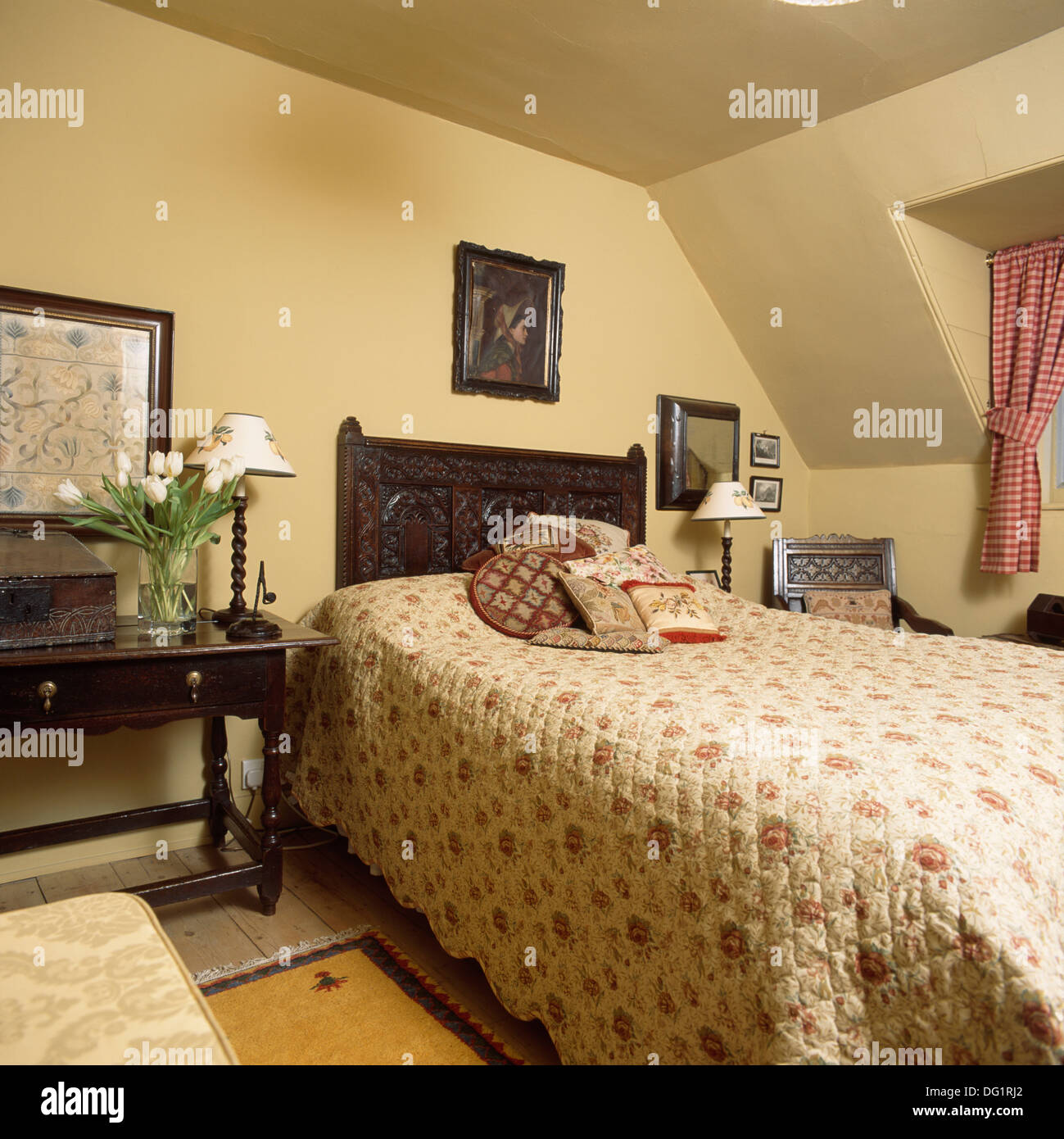 Rose quilt modellato sul letto con testata del letto in legno intagliato nella camera da letto del paese con antichi comodino Foto Stock