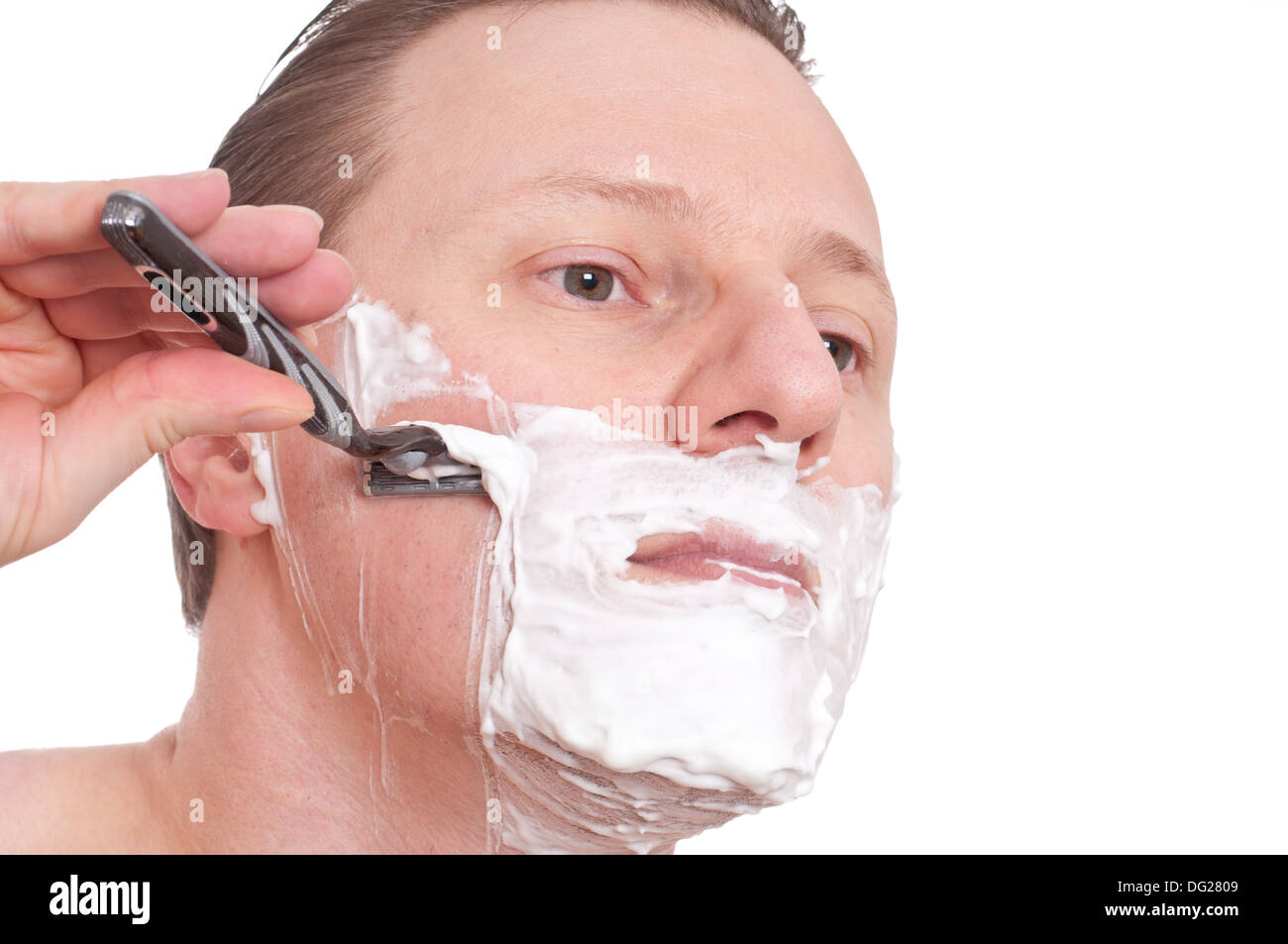 Un uomo con schiuma da barba è la rasatura la guancia Foto stock - Alamy