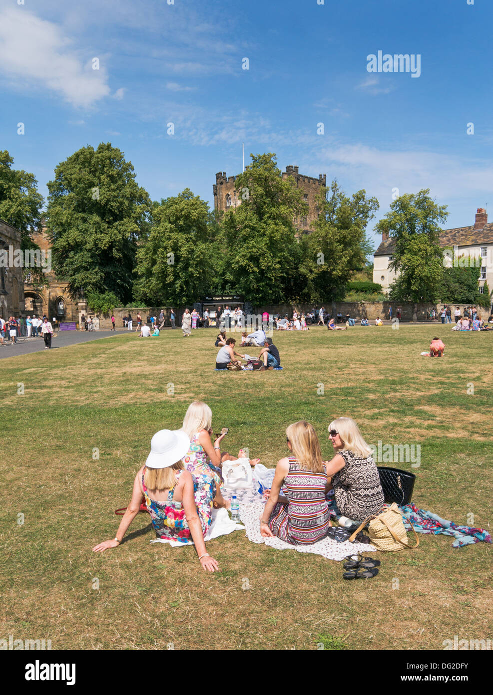 Un gruppo di giovani donne seduti su Durham Palace verde con il castello tenere in background, North East England Regno Unito Foto Stock