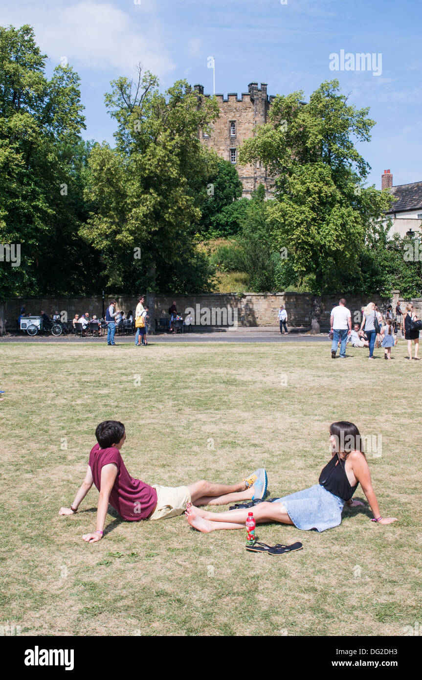 Giovane seduto su Durham Palace verde con il castello tenere in background, North East England Regno Unito Foto Stock