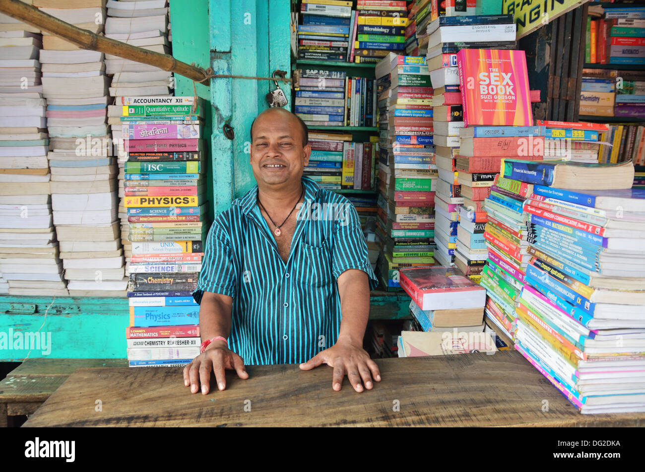 Prenota venditore sorride all'interno del suo negozio nel College Street in Kolkata, India Foto Stock