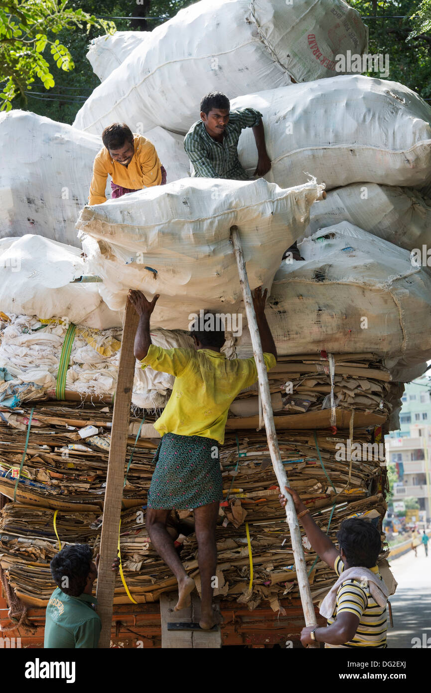 Indian uomini il sovraccarico di un carrello con rifiuti domestici per il riciclaggio. Andhra Pradesh, India Foto Stock