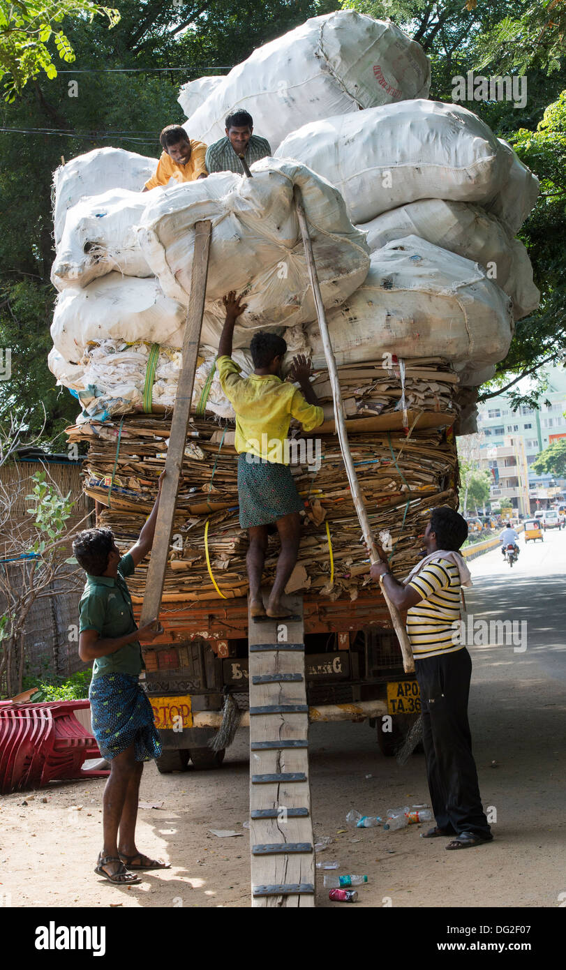 Indian uomini il sovraccarico di un carrello con rifiuti domestici per il riciclaggio. Andhra Pradesh, India Foto Stock