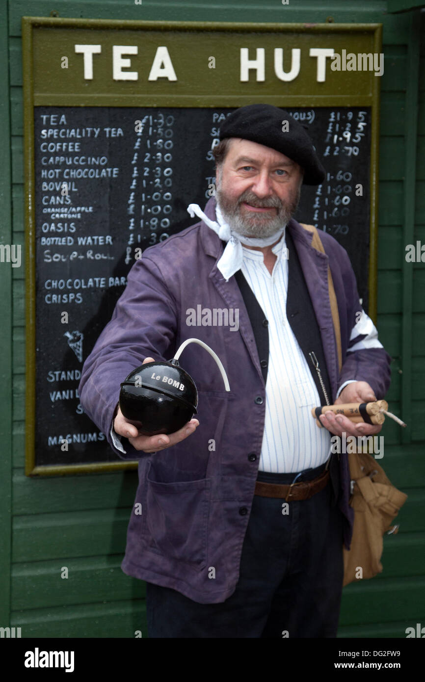 Resistenza francese a Levisham. North Yorkshire, Regno Unito. 11 ottobre, 2013. Signor Mike Thompson, Terzo Reich Luftwaffe operaio di fabbrica tenendo una bomba presso la "Ferrovia in tempo di guerra' Nord nello Yorkshire Moors Railway (NYMR) evento a Levisham stazione ferroviaria in condizioni di tempo inclemente sul weekend 12 -13 ottobre 2013. Stazione Levisham era decorato con periodo di poster e insegne francesi durante il (NYMR) "Weekend di guerra" di diventare 'Le Visham' nel nord della Francia. La raccolta, una ricreazione di un villaggio francese occupato dalle truppe tedesche, essendo parte del 'Allo Allo'-style spensierati e divertenti dell'umore. Foto Stock
