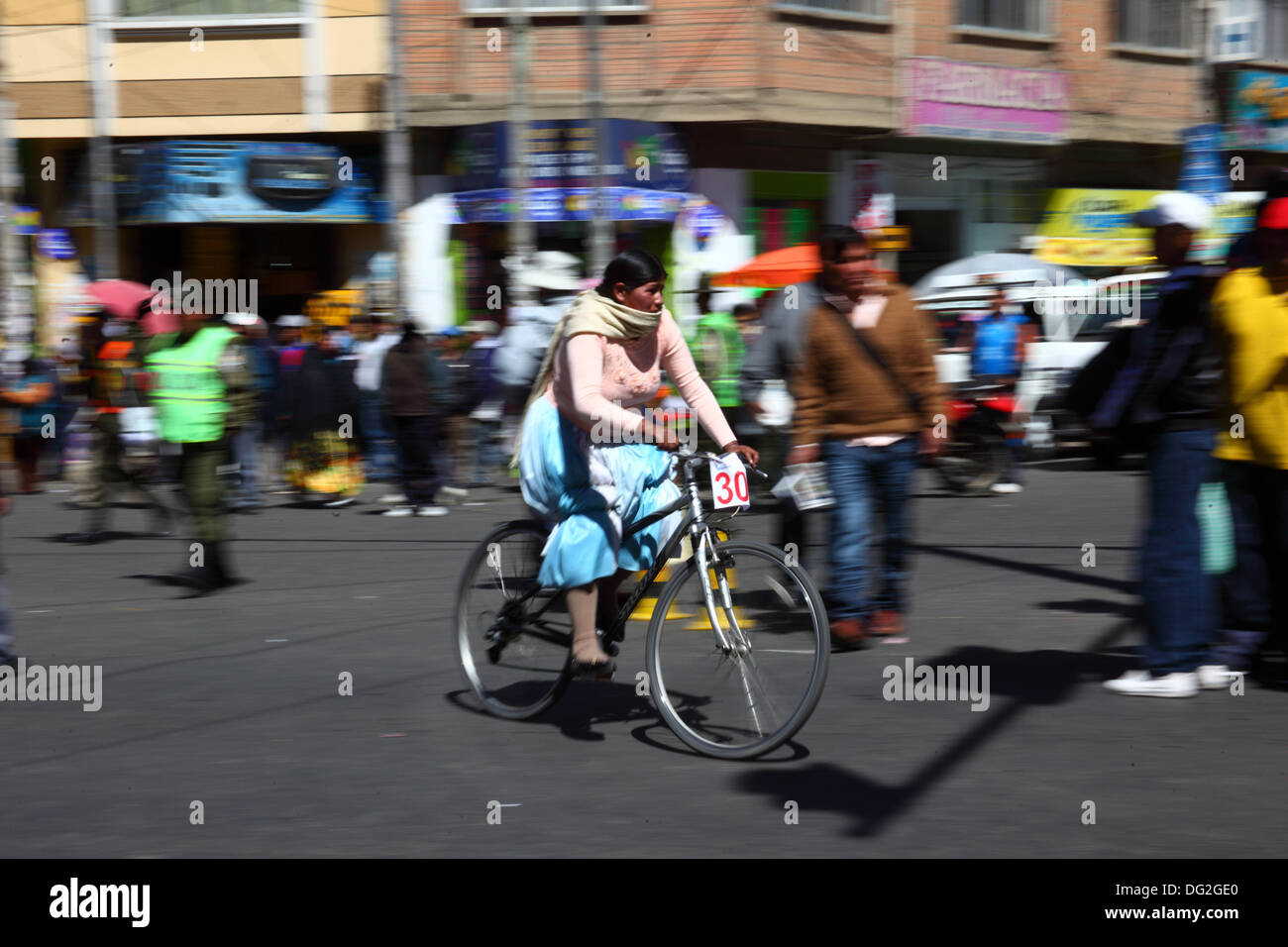 El alto, Bolivia. 12 ottobre 2013. Una concorrente supera gli spettatori mentre prende parte a una corsa di biciclette Cholitas per donne indigene Aymara. La gara si svolge ad un'altitudine di poco più di 4.000 m lungo le strade principali della città di El alto (sopra la Paz) per la giornata boliviana delle donne, che si è svolta ieri venerdì 11 ottobre. Crediti: James Brunker / Alamy Live News Foto Stock