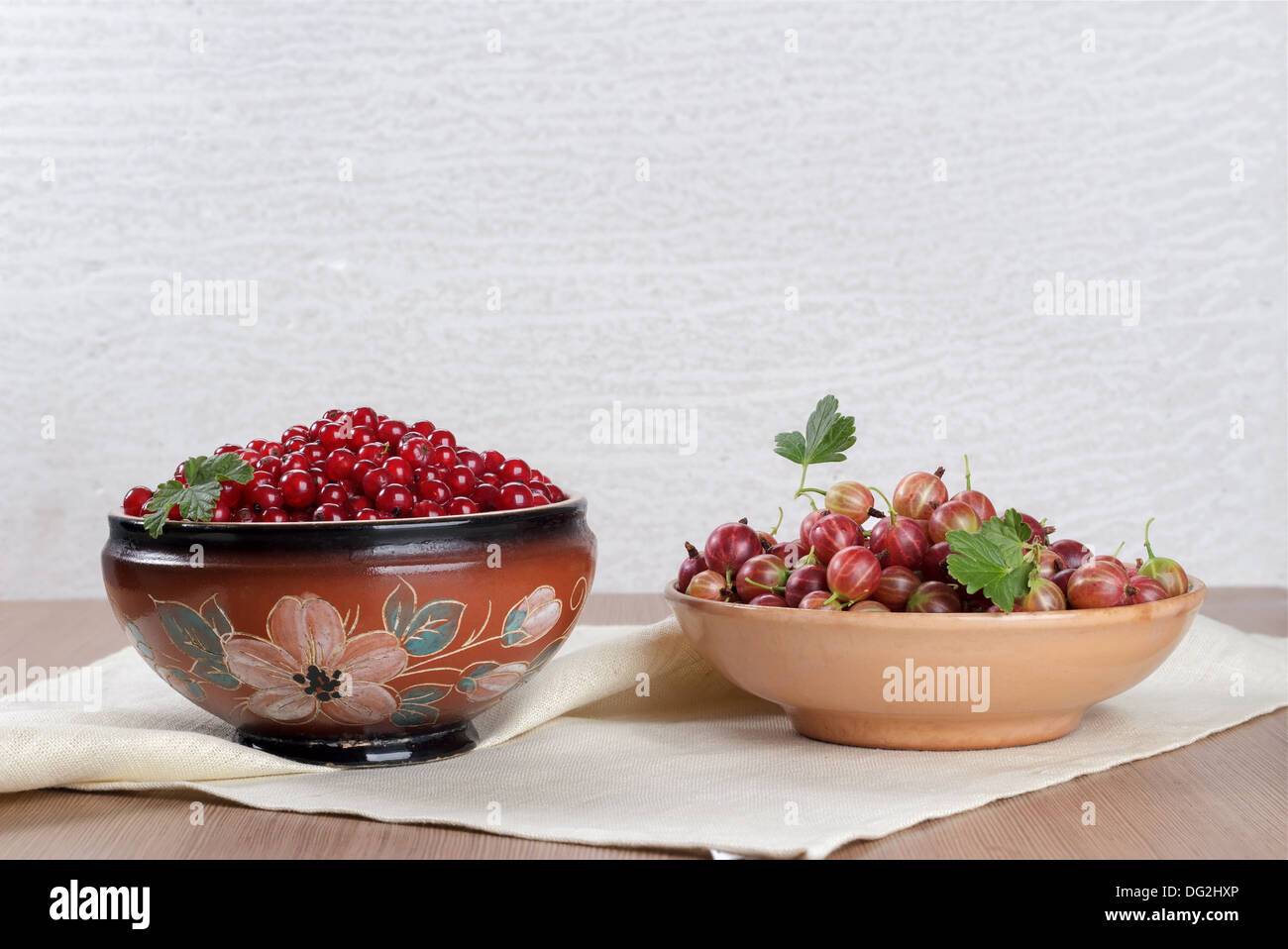 Due tazza ceramica con frutti di bosco freschi ribes a grappoli e uva spina Foto Stock