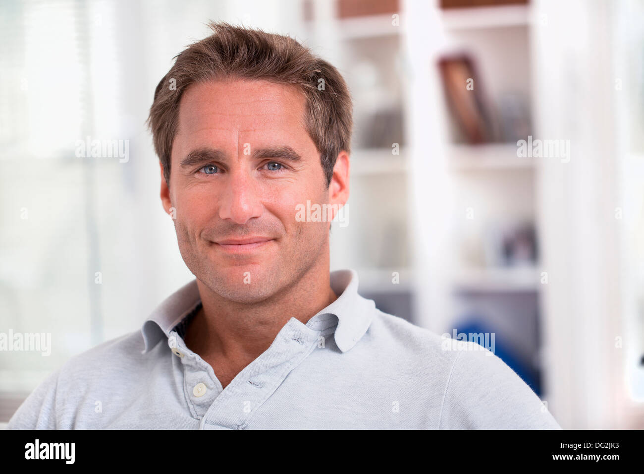 Voce maschile seduto sul divano in un momento di relax a casa cercando di fotocamera a sorridere Foto Stock