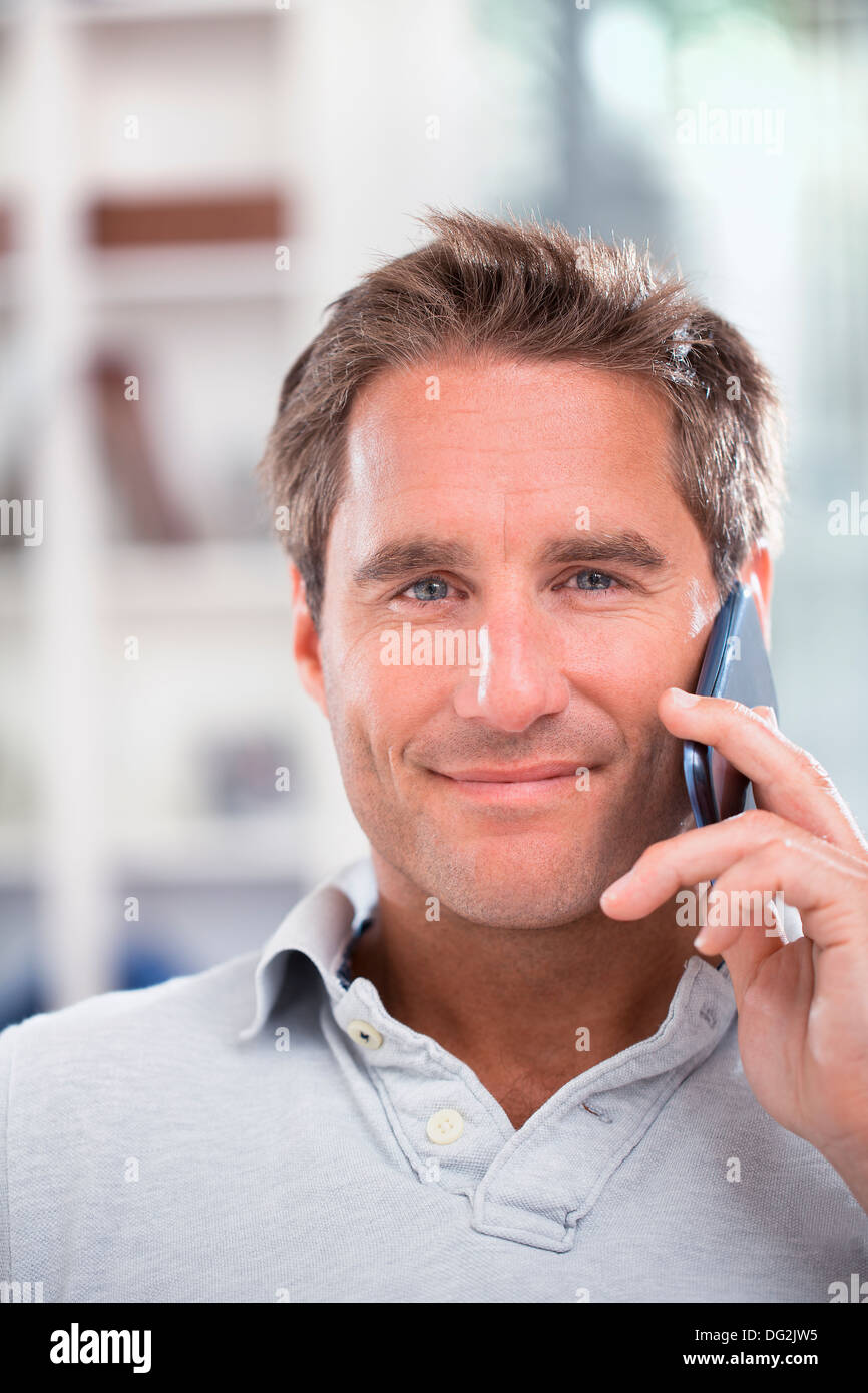 Felice maschio maturo parlando al telefono mobile indoor Foto Stock