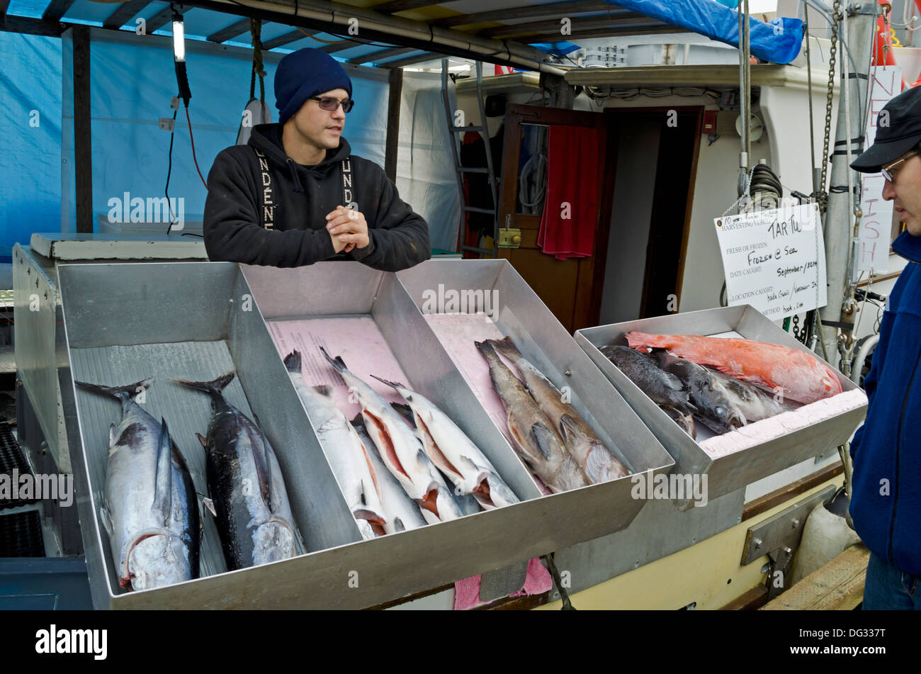 L'uomo la vendita di pesce fresco fuori del Tar tu barca da pesca al molo del mercato del pesce nel villaggio di Steveston, British Columbia, Canada Foto Stock