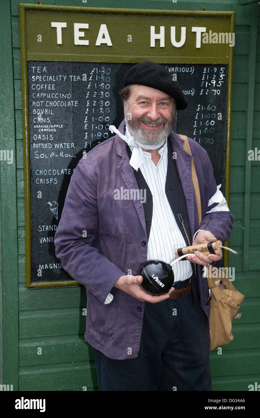 Capanna di tè e menu a Levisham. North Yorkshire, Regno Unito. 11 ottobre, 2013. Signor Mike Thompson, Terzo Reich Luftwaffe operaio di fabbrica tenendo una bomba presso la "Ferrovia in tempo di guerra' Nord nello Yorkshire Moors Railway (NYMR) evento a Levisham stazione ferroviaria in condizioni di tempo inclemente sul weekend 12 -13 ottobre 2013. Stazione Levisham era decorato con periodo di poster e insegne francesi durante il (NYMR) "Weekend di guerra" di diventare 'Le Visham' nel nord della Francia. La raccolta, una ricreazione di un villaggio francese occupato dalle truppe tedesche, essendo parte del 'Allo Allo'-style spensierati e divertenti dell'umore. Foto Stock