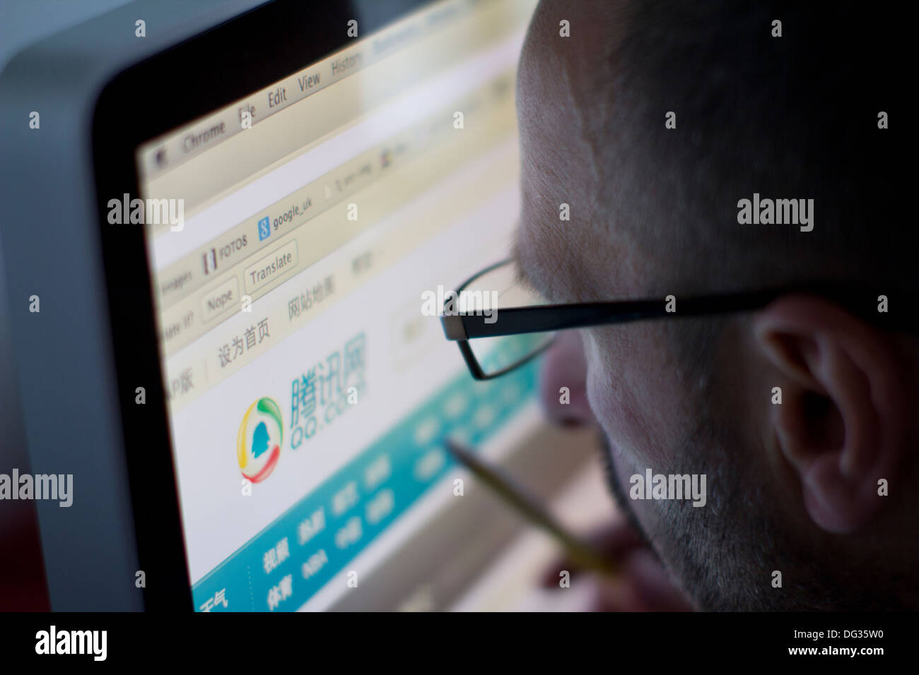 Un uomo adulto che naviga sul sito web Tencent QQ su un computer desktop, illustrando l'uso della popolare piattaforma di messaggistica istantanea cinese e dei servizi di comunicazione digitale sviluppati dal gigante tecnologico Tencent Foto Stock