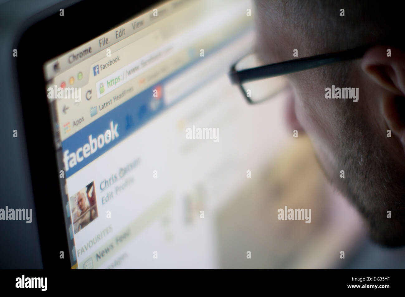 Un uomo adulto visualizza la homepage di Facebook, la piattaforma globale di social media, su un computer desktop, evidenziando la connettività digitale e la comunicazione online Foto Stock