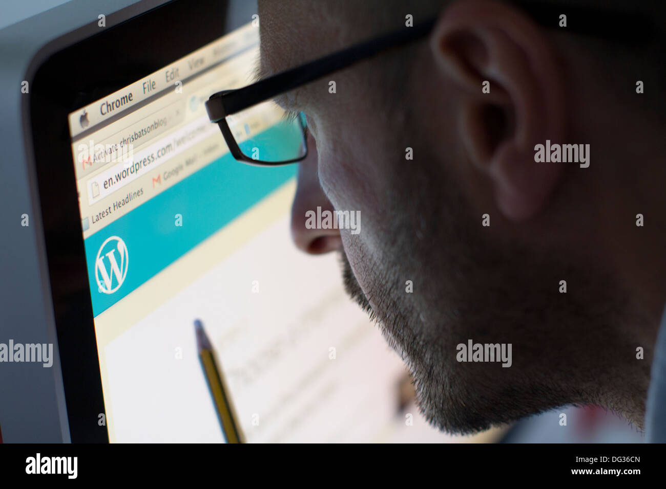 Uomo adulto che naviga sul sito Web di WordPress su un computer desktop, evidenziando l'uso del popolare sistema di gestione dei contenuti (CMS) per blog, creazione di siti Web e pubblicazione digitale Foto Stock