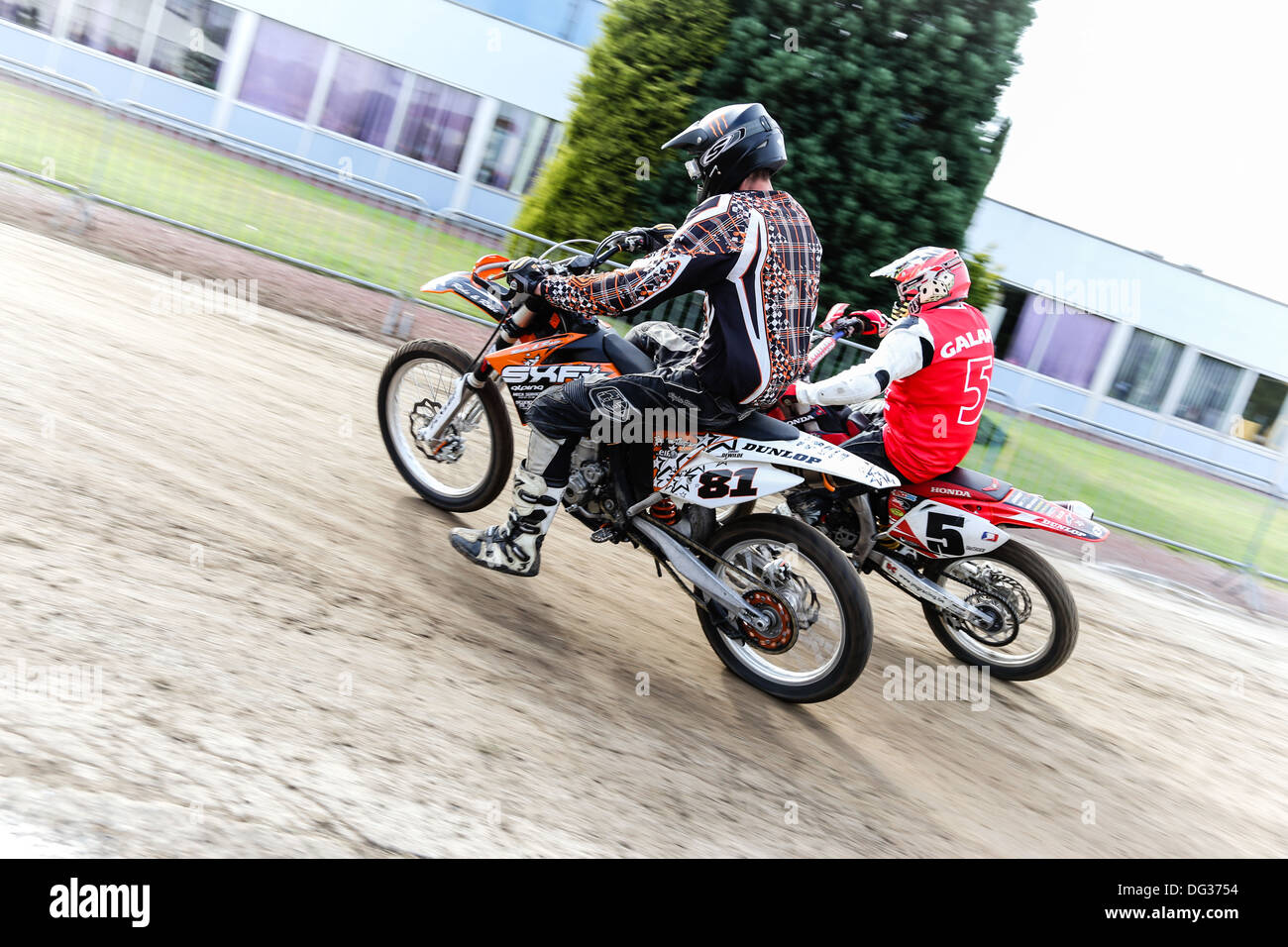 2 supermoto piloti di prendere una curva sulla pista di asfalto. Incentrato su i piloti. Foto Stock