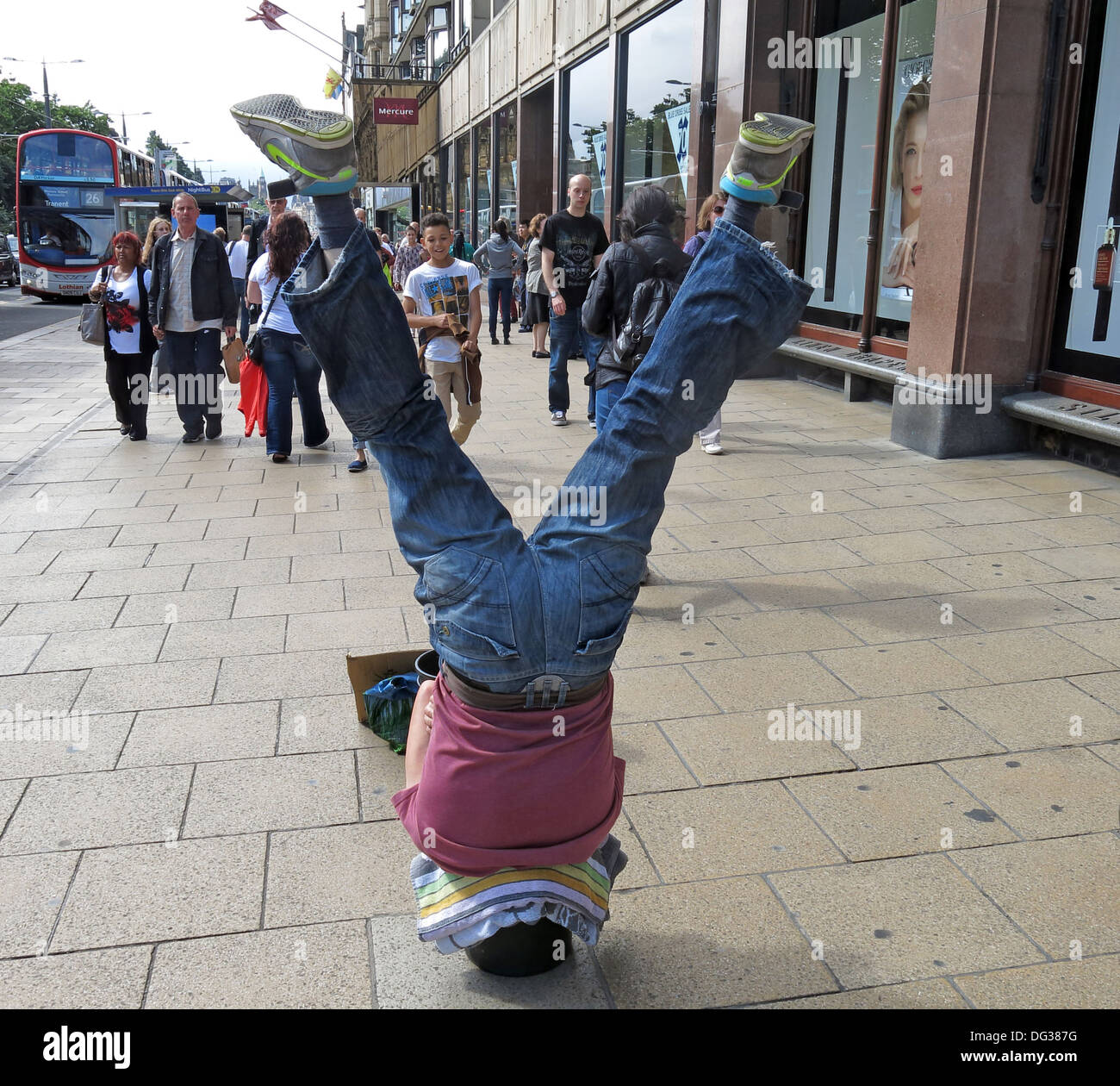 Fringe Busker in Princes St, settimana del Festival di Edimburgo - a testa in giù in un secchio, Scozia, Regno Unito, EH2 2AN Foto Stock