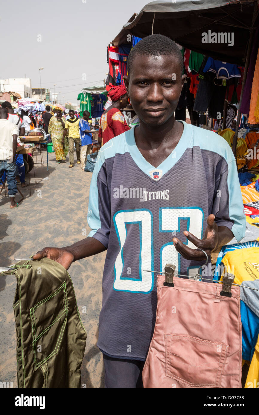 Il Senegal, Touba. Giovane Uomo abbigliamento vendita nel mercato. Foto Stock