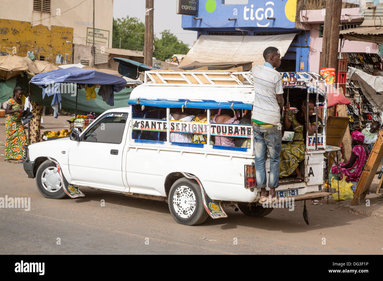 Il Senegal, Touba. Il trasporto locale. Pick-up con i giovani uomini di solito appeso sul retro della scheda In esecuzione, passeggeri all'interno. Foto Stock