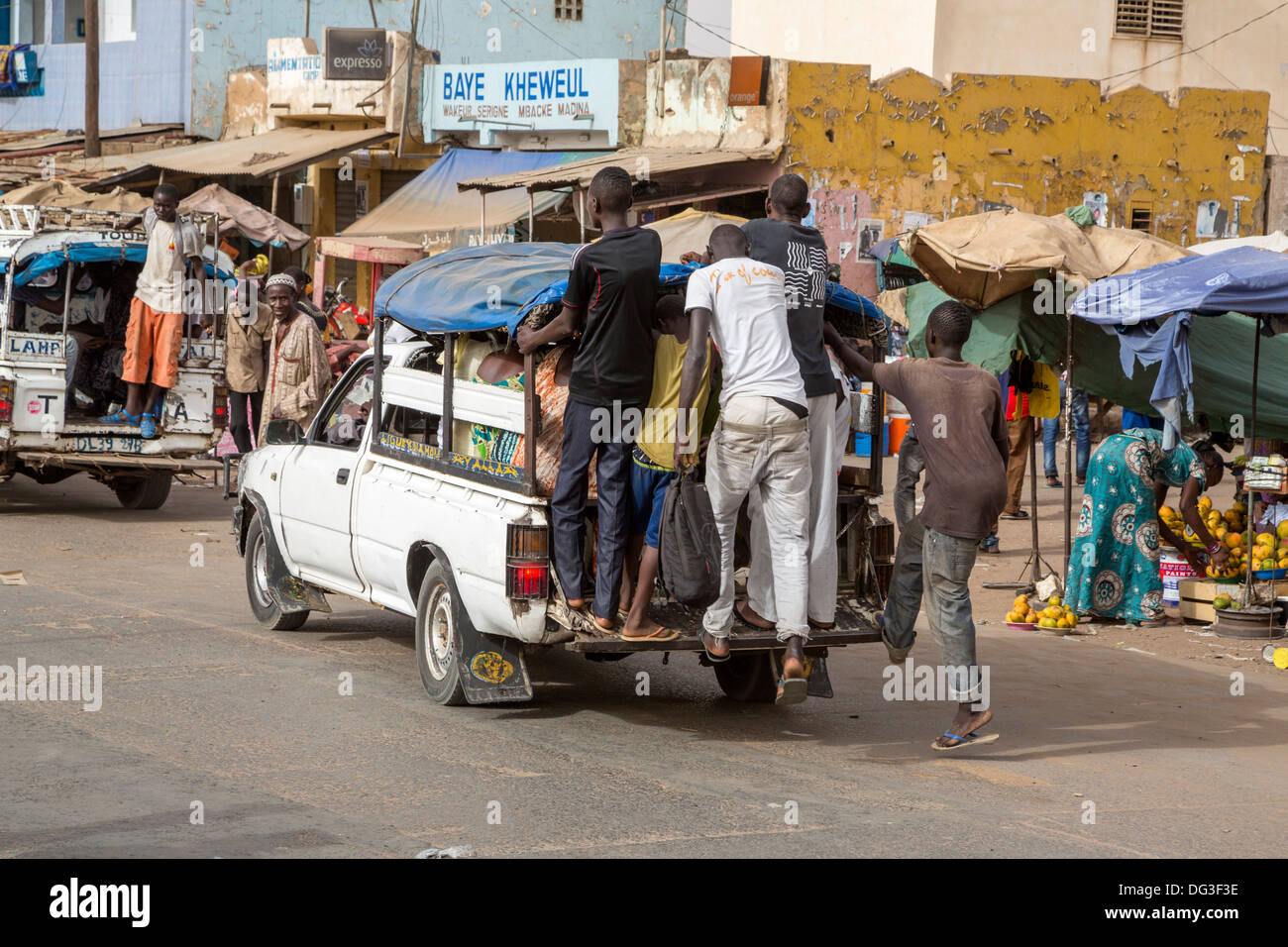 Il Senegal, Touba. Il trasporto locale. Pick-up con i giovani uomini di solito appeso sul retro della scheda In esecuzione, passeggeri all'interno. Foto Stock