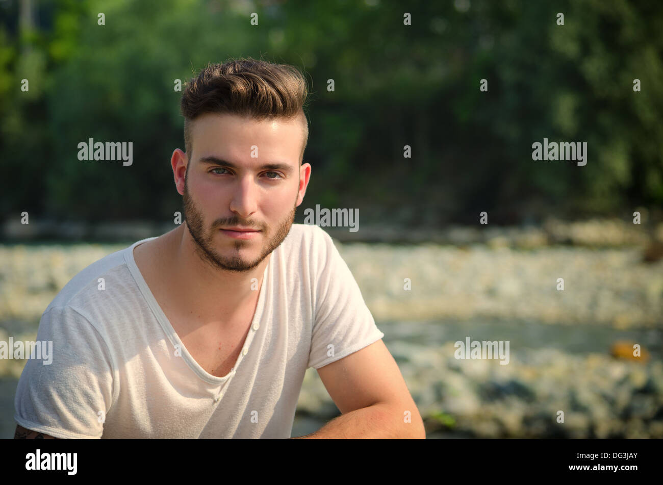 Ritratto di bel giovane in t-shirt bianco all'aperto, cercando nella fotocamera Foto Stock
