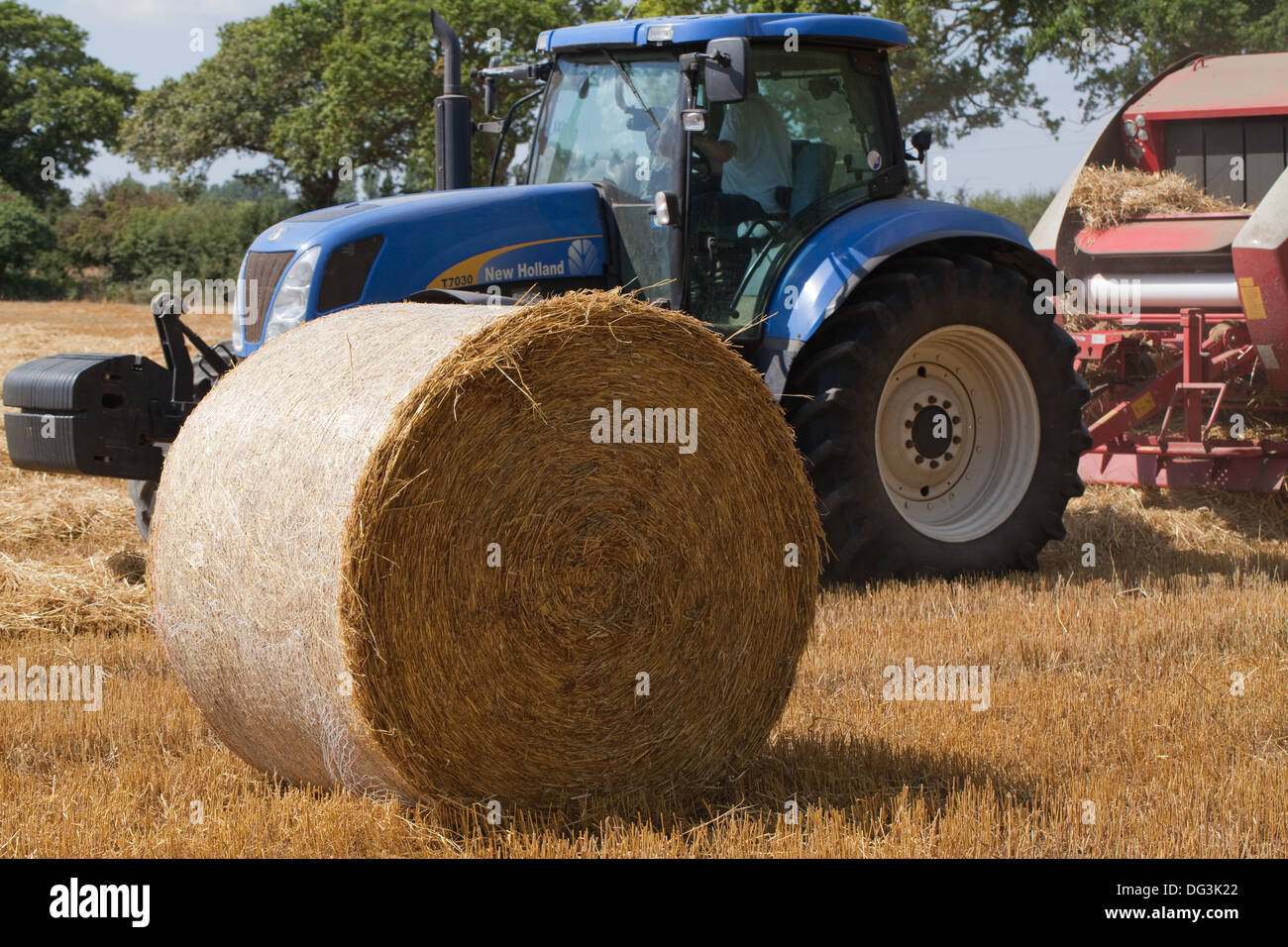 Il trattore disegnato, round macchina compattatrice, lavorando su righe di combinare raccolte paglia. Primo piano della balla. Foto Stock