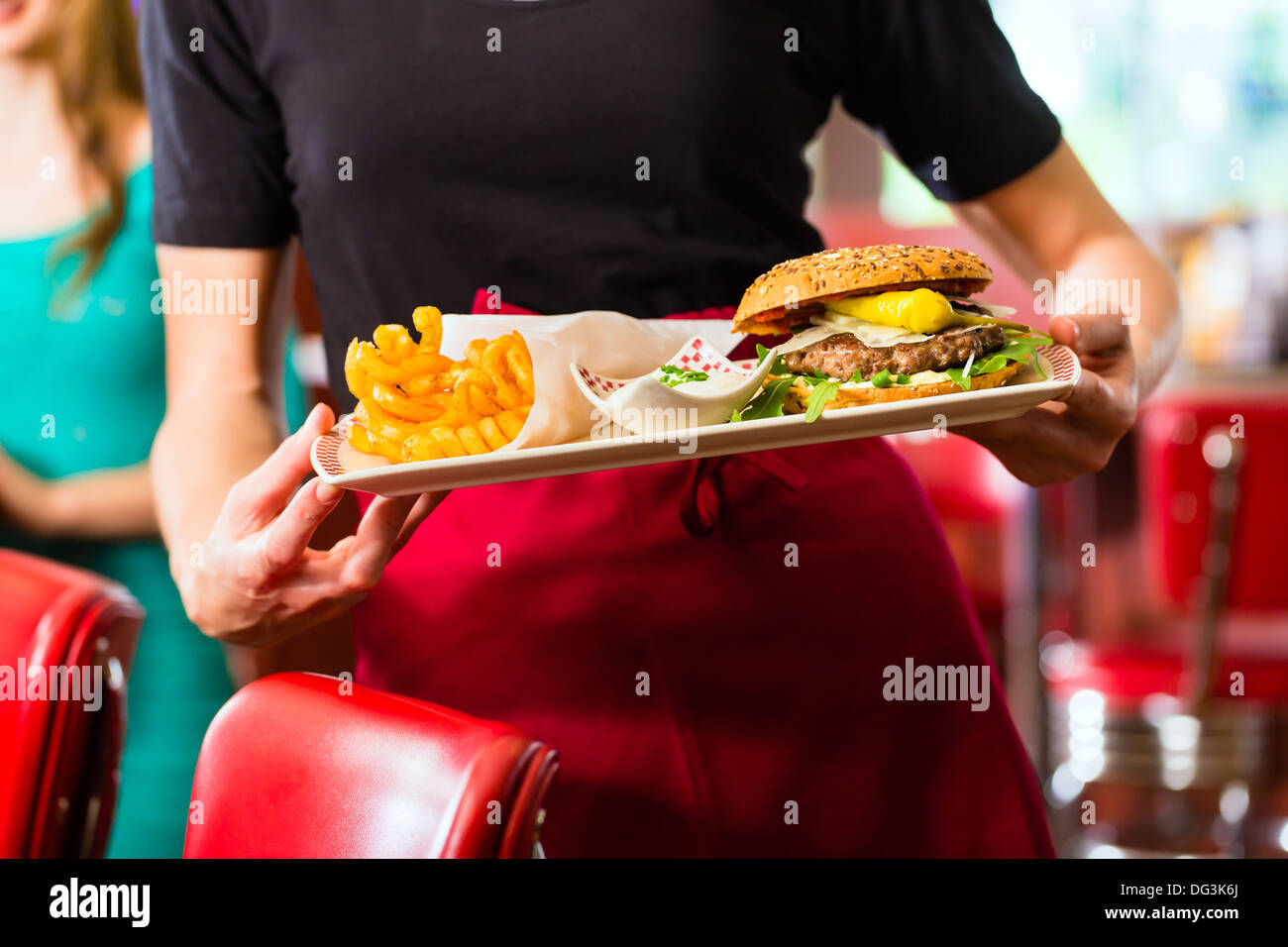 Amici o coppia di mangiare fast food con hamburger e patatine in American fast food diner Foto Stock