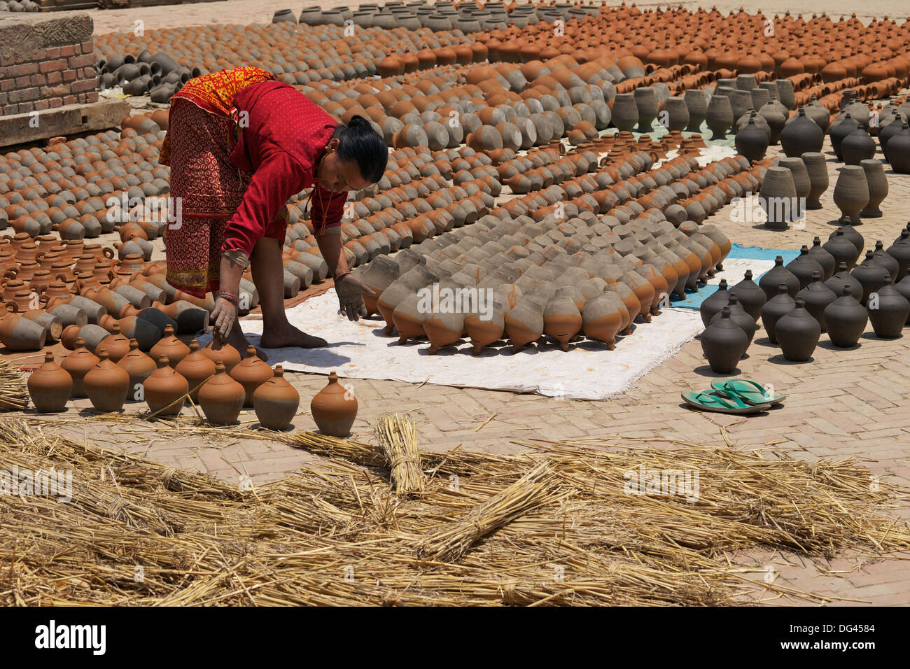 Donna pentole di tornitura ad asciugare al sole, Potter's Square, Bhaktapur, Nepal, Asia Foto Stock