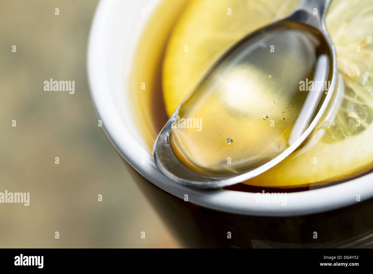 Primo piano orizzontale foto del miele dorato, cucchiaio, con freschi fettina di limone nella calda tazza di tè Foto Stock