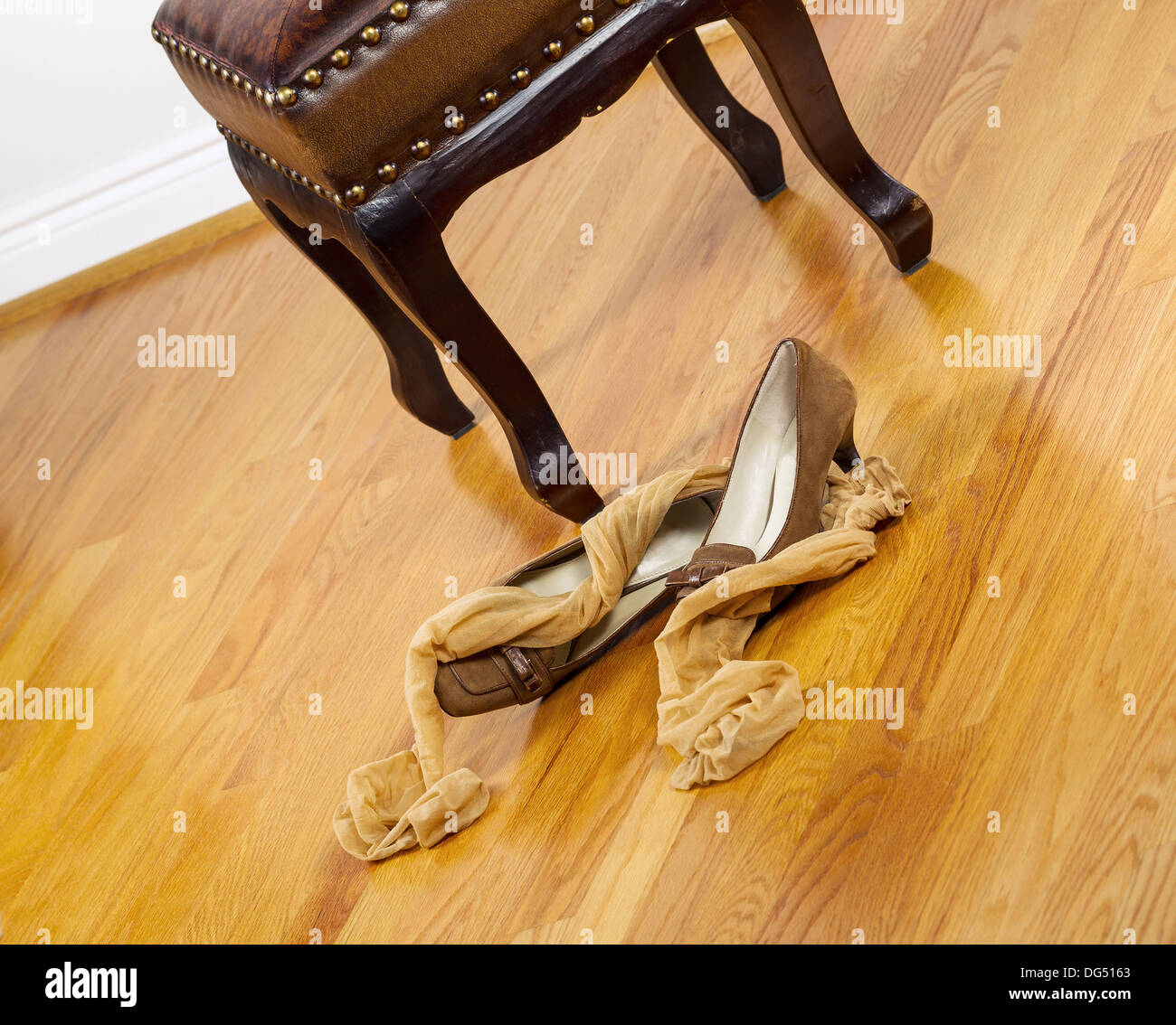 Foto angolata di calze donna abiti e scarpe che giace accanto a Sgabello imbottito con red pavimenti in legno di quercia in background Foto Stock