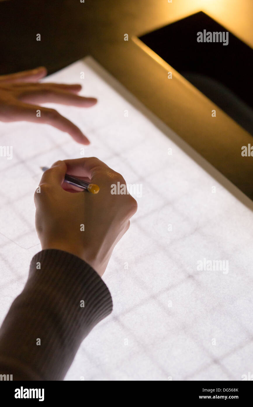 Matita nera in una mano destra sul retro bianco luce sullo sfondo della tabella, l'altra parte è in possesso della carta Foto Stock