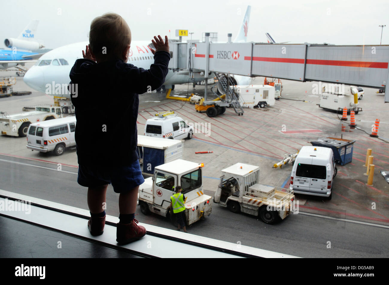 Un giovane ragazzo guardando attraverso una finestra di airport a piani al di fuori Foto Stock