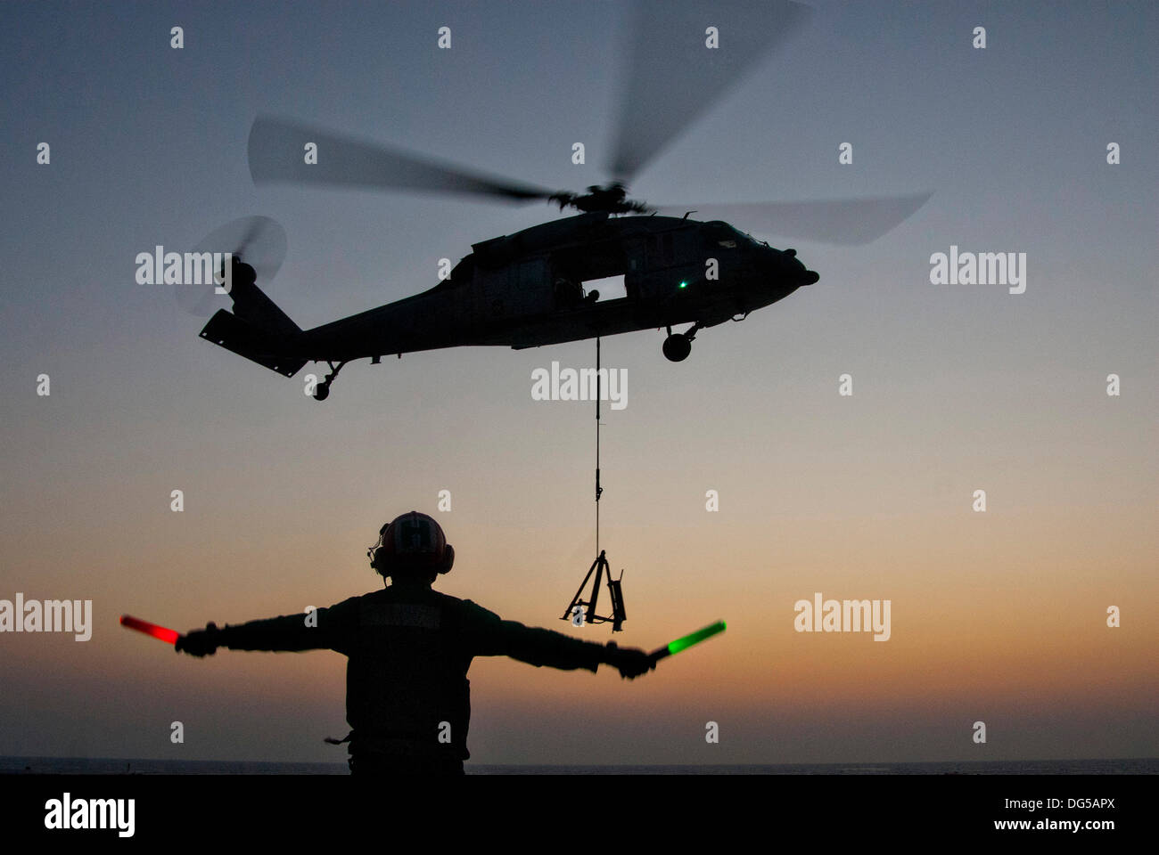 Un US Navy sailor i segnali a MH-60S Seahawk elicottero a terra sul ponte di volo della portaerei USS George Washington durante un rifornimento in mare 14 ottobre 2013 nelle acque ad ovest della penisola coreana. Foto Stock
